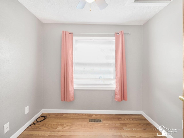 spare room with ceiling fan, wood-type flooring, and a textured ceiling