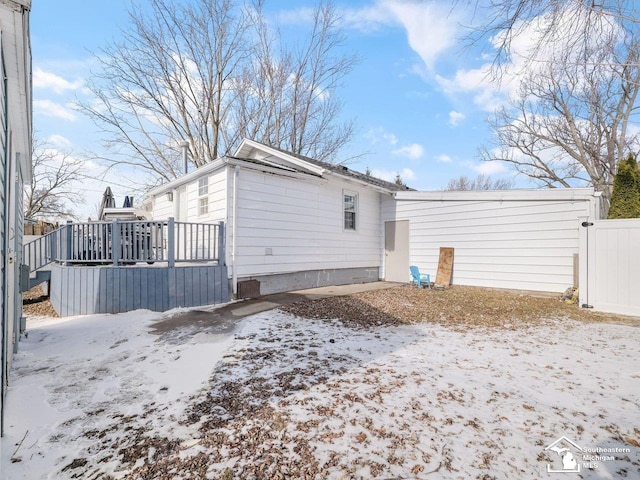 snow covered back of property featuring a deck