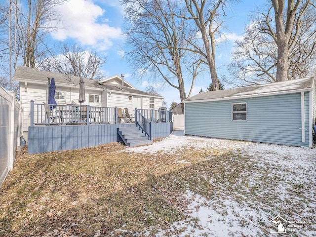 snow covered back of property with a deck