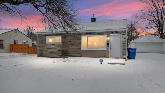 snow covered back of property featuring an outbuilding and a garage