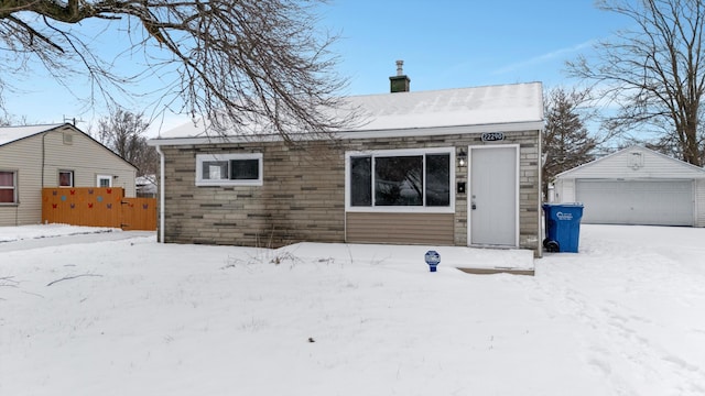 snow covered back of property with an outbuilding and a garage