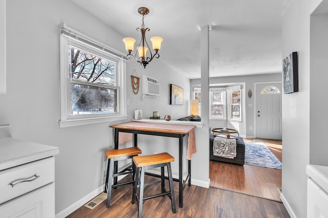 dining space featuring a wall mounted air conditioner, hardwood / wood-style flooring, and a notable chandelier