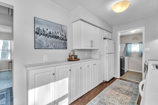 kitchen featuring white fridge, washer and dryer, white cabinets, and dark hardwood / wood-style floors