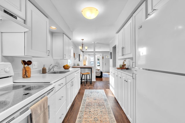 kitchen with dark hardwood / wood-style floors, decorative light fixtures, sink, white cabinets, and white appliances