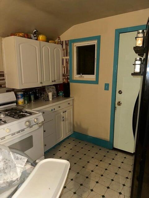 kitchen featuring white gas stove and white cabinets