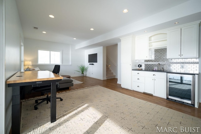 home office featuring wine cooler, sink, and hardwood / wood-style flooring