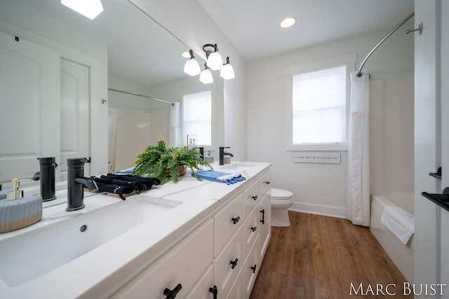 full bathroom featuring hardwood / wood-style flooring, a healthy amount of sunlight, toilet, and vanity