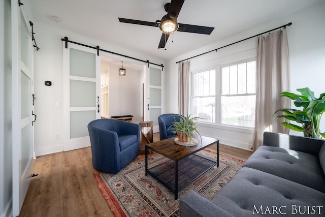 living room featuring hardwood / wood-style flooring, a barn door, and ceiling fan