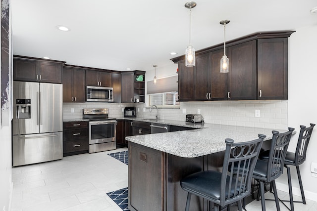 7500 Dexter Pinckney Rd, Dexter, MI 48130 - kitchen featuring appliances with stainless steel finishes, sink, hanging light fixtures, kitchen peninsula, and dark brown cabinets
