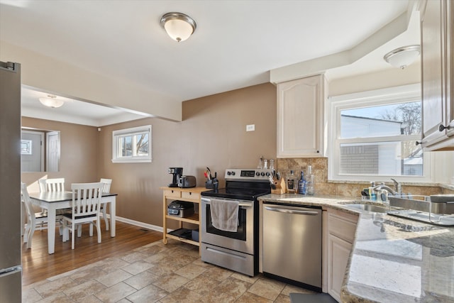 kitchen with light stone counters, stainless steel appliances, sink, and decorative backsplash