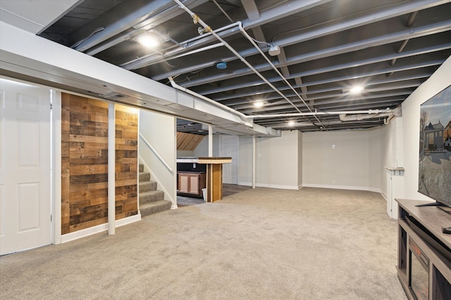 basement with light carpet and wooden walls