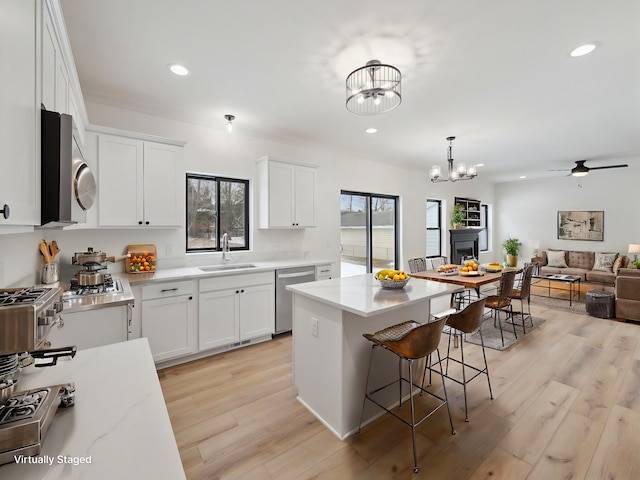 kitchen with stainless steel appliances, open floor plan, white cabinets, and a sink