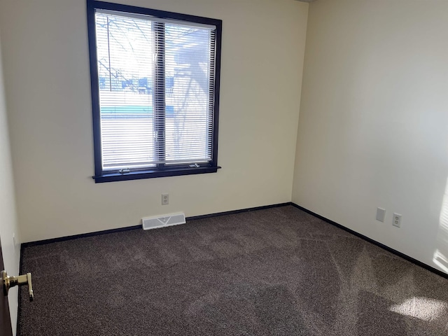 empty room featuring a wealth of natural light and dark colored carpet