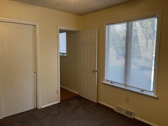 unfurnished bedroom featuring a closet and dark colored carpet