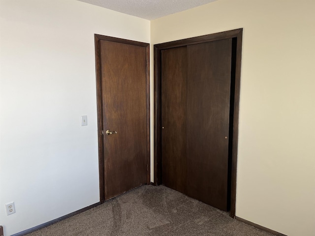 unfurnished bedroom featuring dark carpet, a closet, and a textured ceiling