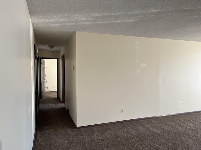 empty room with a textured ceiling and dark colored carpet