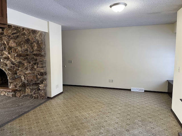 interior space with a stone fireplace and a textured ceiling