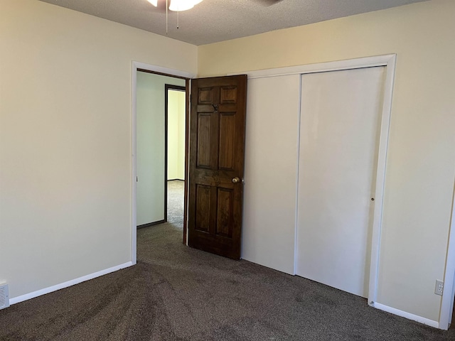 unfurnished bedroom featuring dark carpet, a closet, and a textured ceiling