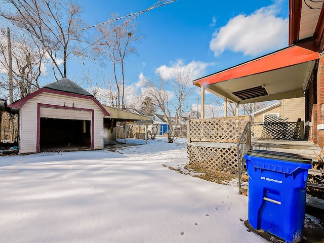 snowy yard with a garage and an outdoor structure