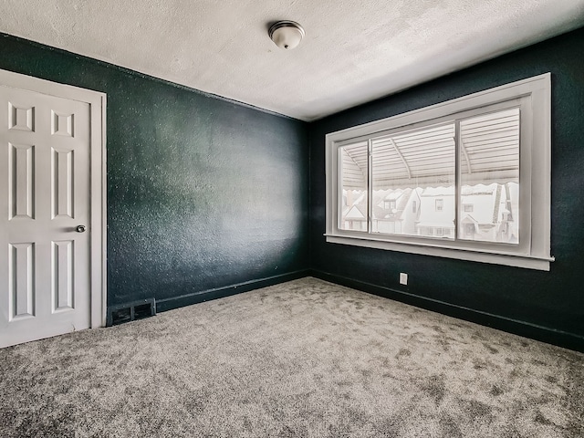 carpeted empty room featuring a textured ceiling