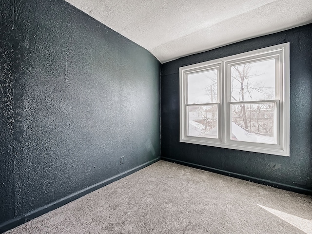 unfurnished room featuring vaulted ceiling, a textured ceiling, and carpet