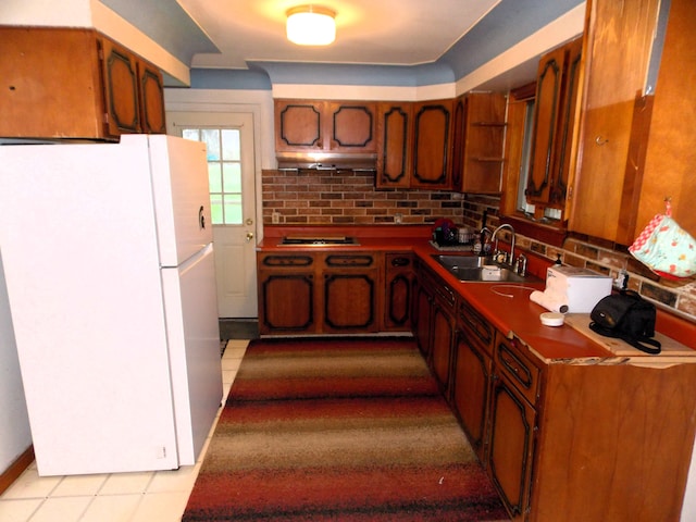 kitchen with white refrigerator, cooktop, and sink