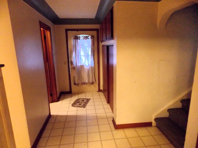 hall with stairway, light tile patterned floors, and baseboards