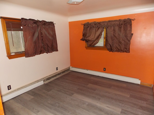 unfurnished room with a baseboard radiator, baseboards, and wood finished floors