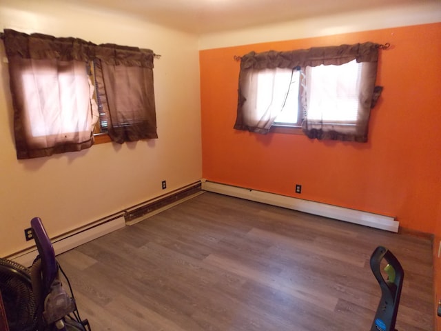 unfurnished room with baseboard heating and wood finished floors