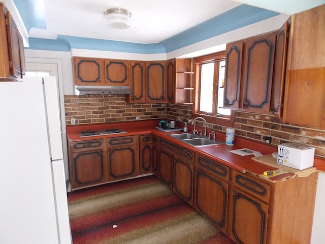 kitchen with decorative backsplash, electric stovetop, freestanding refrigerator, and a sink