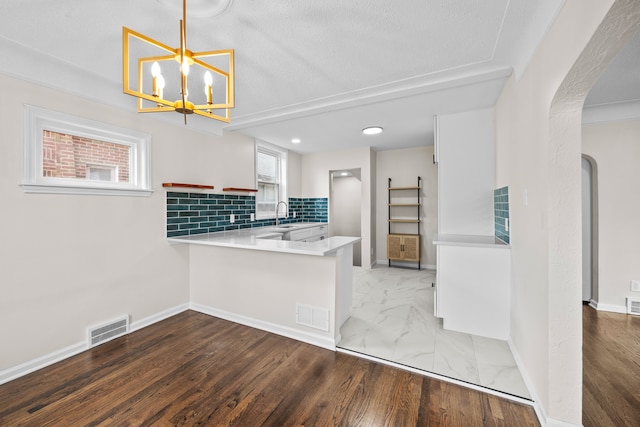 kitchen featuring pendant lighting, tasteful backsplash, dark hardwood / wood-style flooring, a notable chandelier, and kitchen peninsula