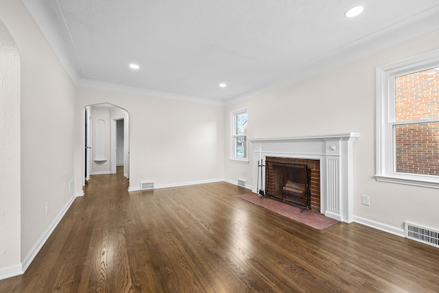 unfurnished living room featuring a fireplace, ornamental molding, and dark hardwood / wood-style flooring