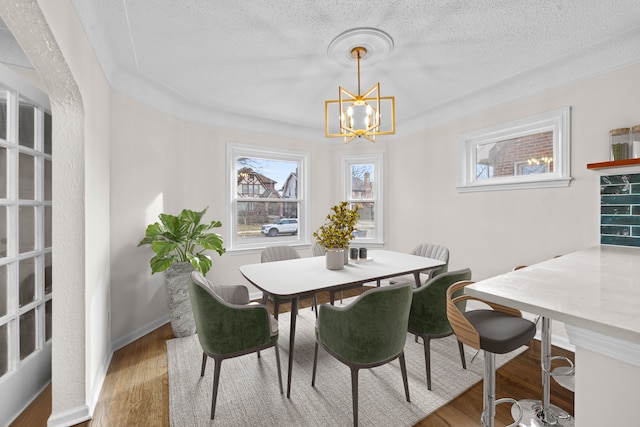 dining room with hardwood / wood-style floors, a textured ceiling, and an inviting chandelier