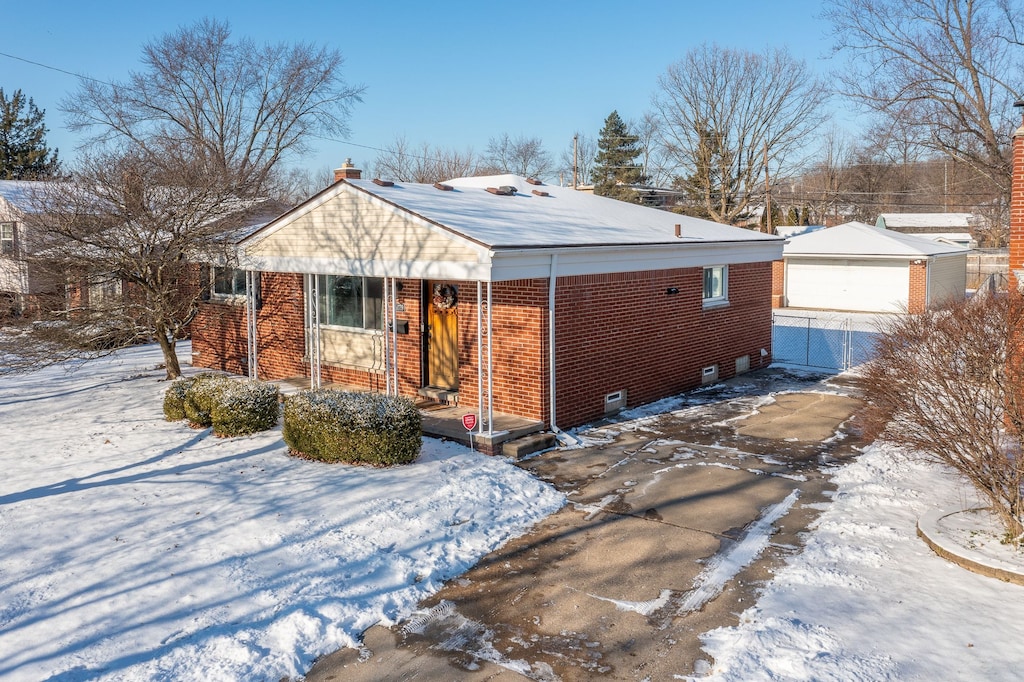 snow covered back of property featuring a garage and an outdoor structure