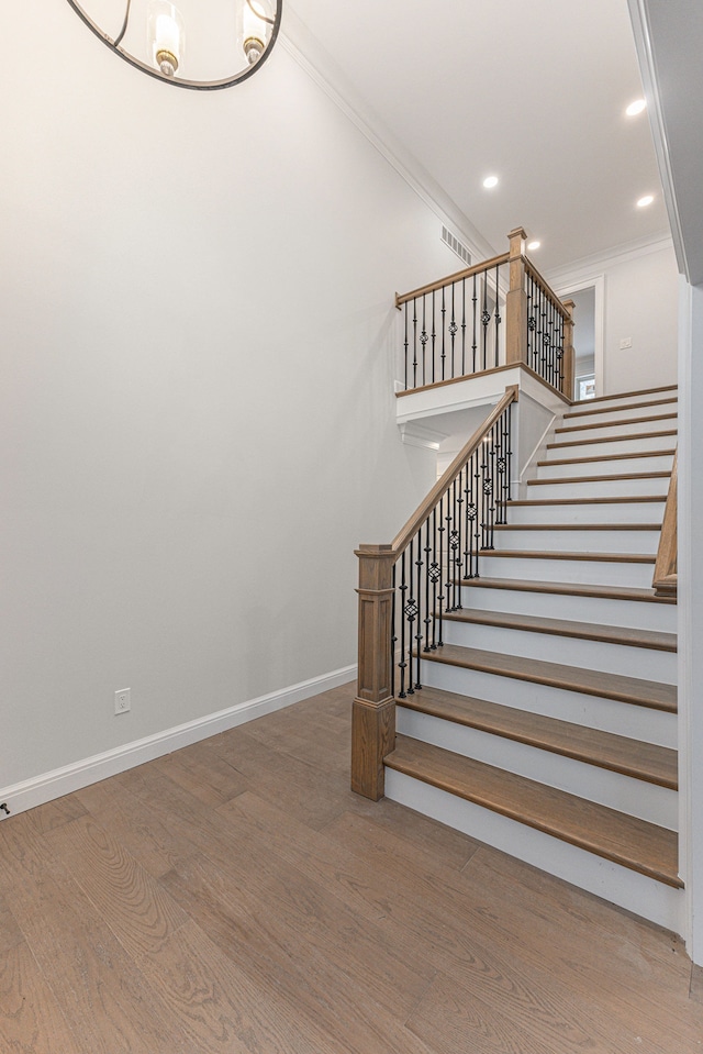 stairway featuring ornamental molding and wood-type flooring