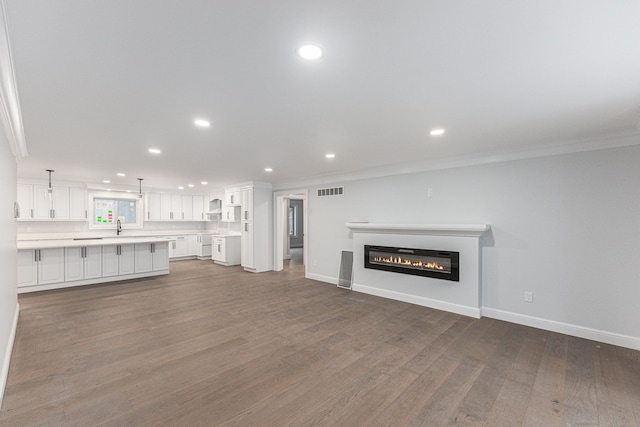 unfurnished living room featuring dark wood-type flooring and ornamental molding