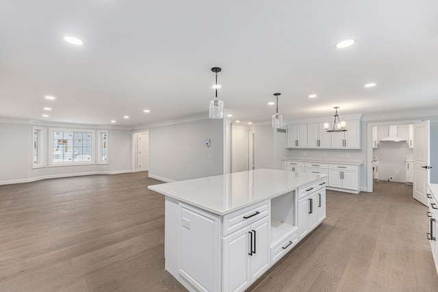 kitchen with pendant lighting, light hardwood / wood-style flooring, white cabinetry, a center island, and ornamental molding