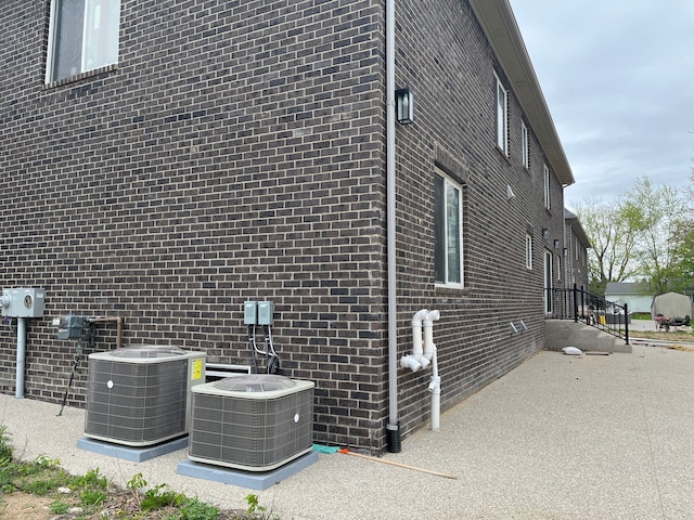 view of side of home with central air condition unit, a patio area, and brick siding