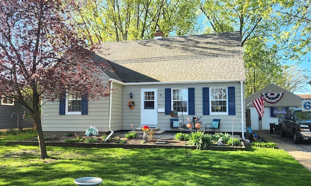 view of front facade with a chimney, a shingled roof, and a front yard