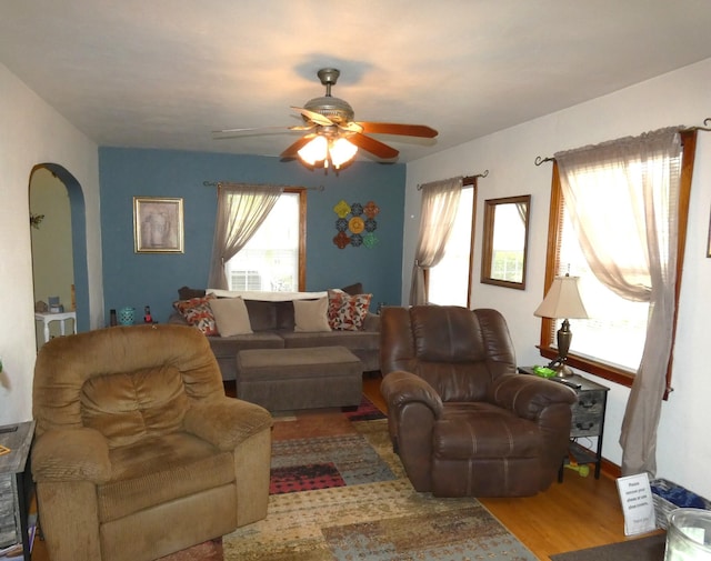 living room with ceiling fan, wood finished floors, and arched walkways