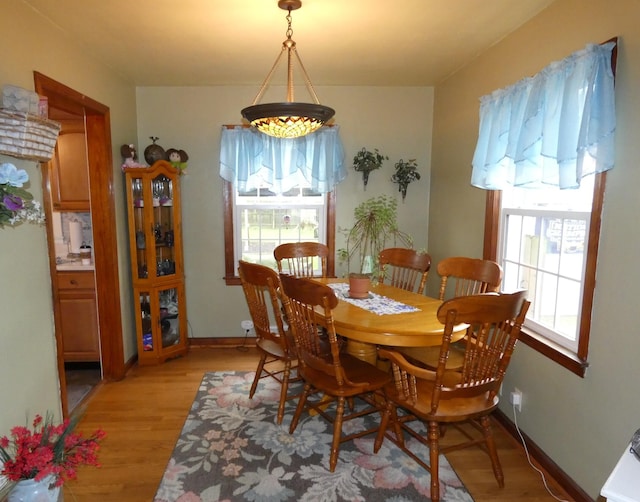 dining area with light wood-style flooring, baseboards, and a healthy amount of sunlight