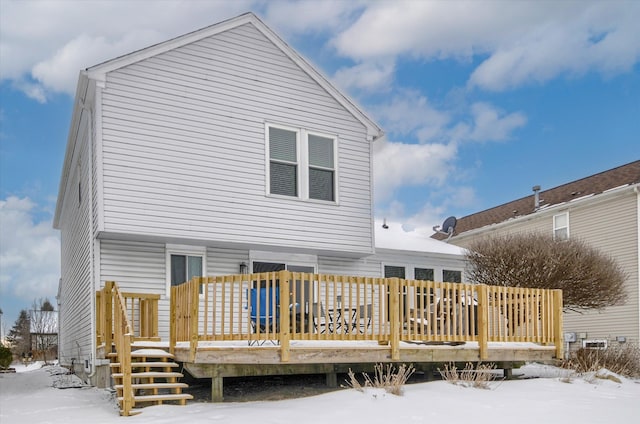 snow covered rear of property with a deck