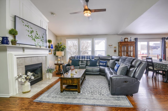 living room with hardwood / wood-style flooring, lofted ceiling, a tiled fireplace, and a wealth of natural light