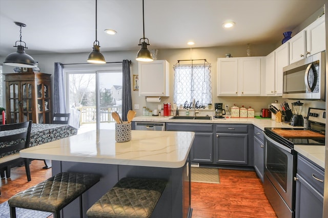 kitchen featuring sink, gray cabinetry, white cabinetry, appliances with stainless steel finishes, and pendant lighting