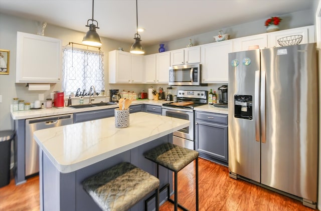 kitchen featuring white cabinetry, stainless steel appliances, sink, and a kitchen island