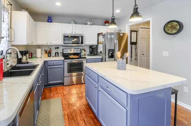 kitchen featuring sink, white cabinetry, a center island, appliances with stainless steel finishes, and pendant lighting