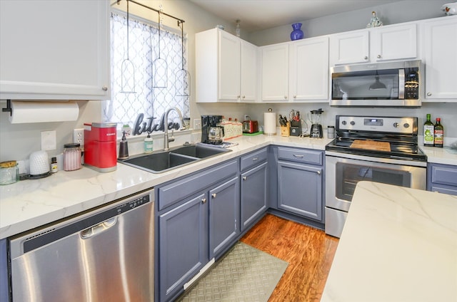 kitchen featuring sink, white cabinets, light hardwood / wood-style floors, stainless steel appliances, and light stone countertops