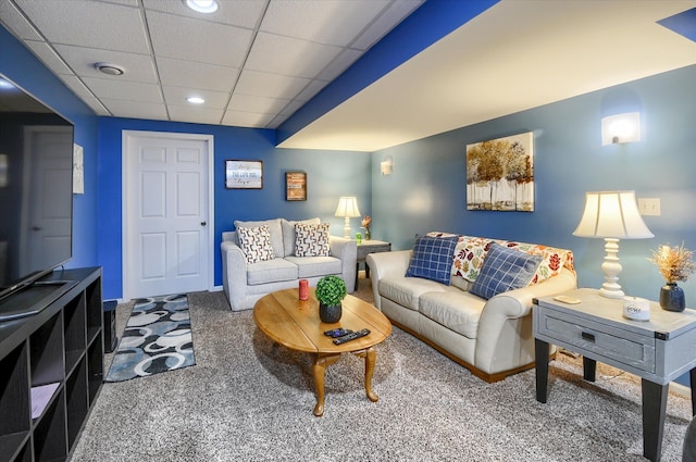 carpeted living room featuring a drop ceiling