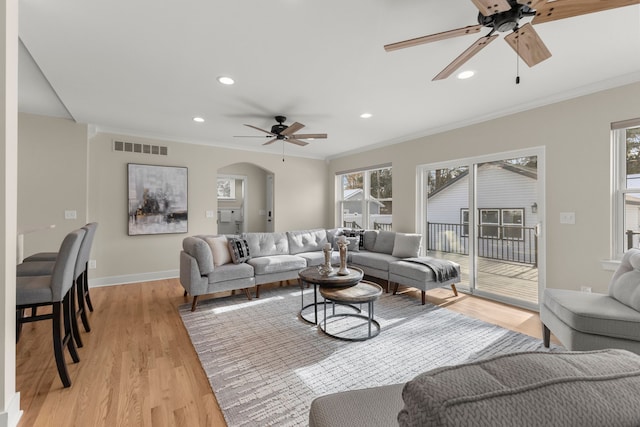 living room featuring crown molding, a wealth of natural light, ceiling fan, and light hardwood / wood-style flooring