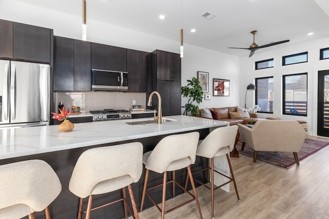 kitchen with tasteful backsplash, appliances with stainless steel finishes, a kitchen breakfast bar, and sink